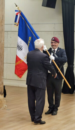 16 décembre 2025 à Noisy le Roi : le Délégué Départemental Ile de France de l’AICS-SR Stéphane Jah reçoit le drapeau et la médaille d’or de l’AICS-SR par Yves Fournier Président de l’AICS-SR